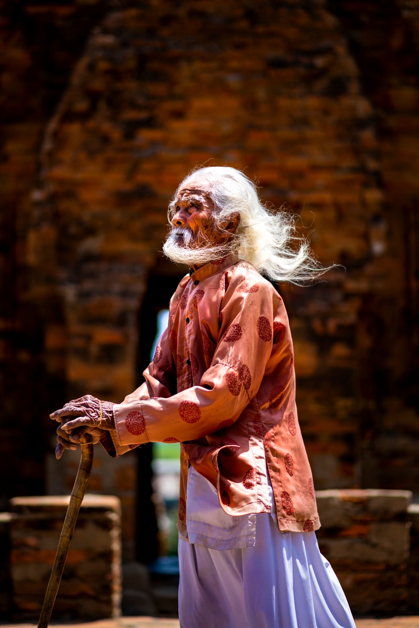Elderly man in traditional dress, white hair and beard blowing in the wind, side profile