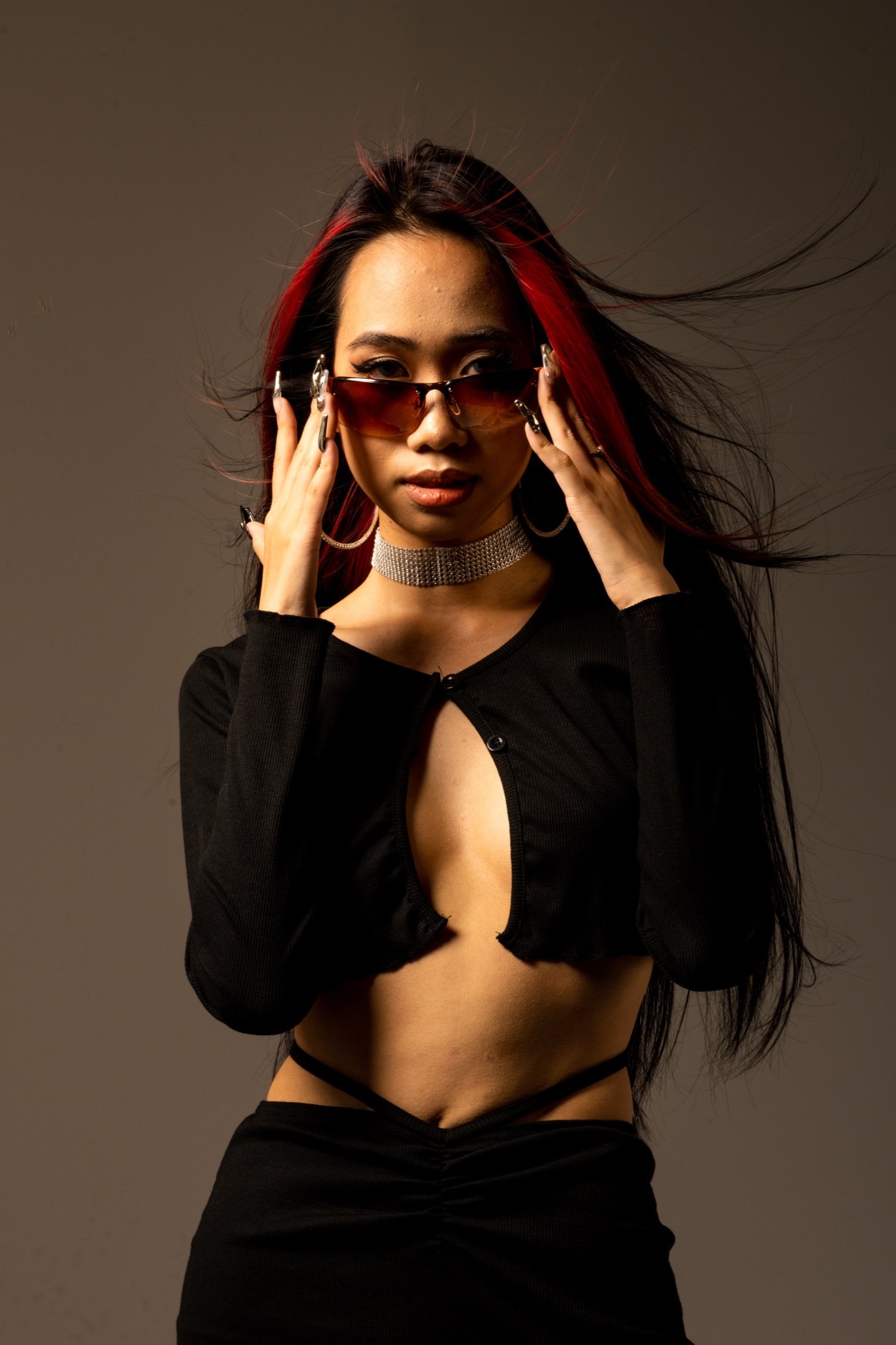 Studio fashion portrait with red-streaked hair and warm red-toned lighting