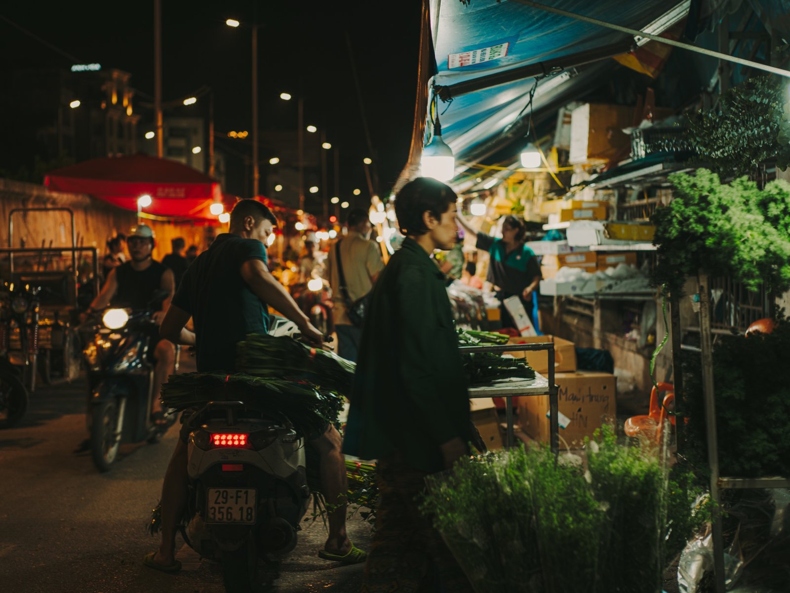 Night flower market scene with vendors, motorbikes, and string lights